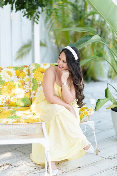 Woman in a yellow dress seated in a colorful South Florida setting